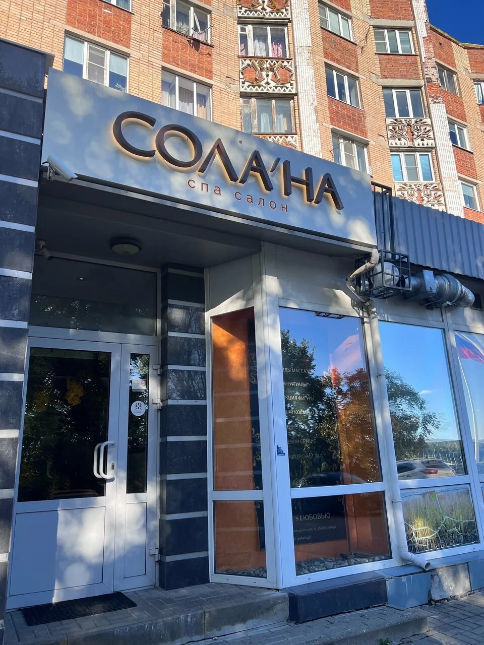 Вход в спа-салон: вывеска «Сола’на» над стеклянной дверью